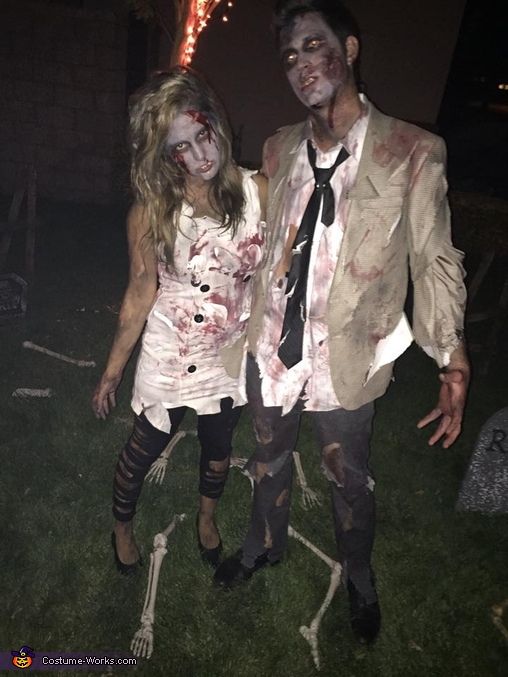 two people dressed up in zombie costumes standing next to each other on the grass at night