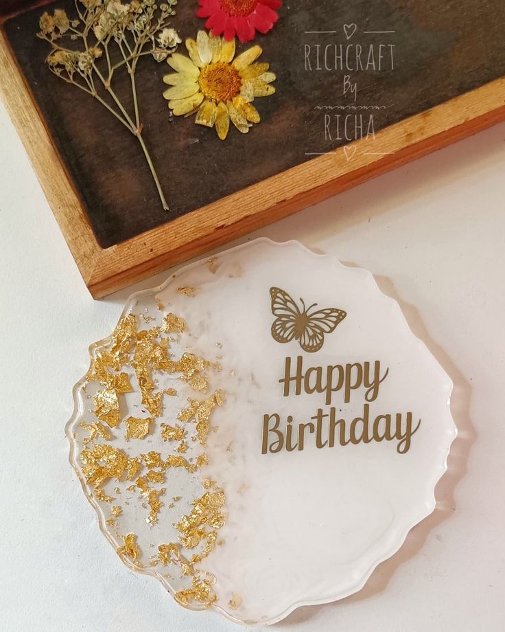 a white plate with gold glitters on it next to a wooden box and flowers