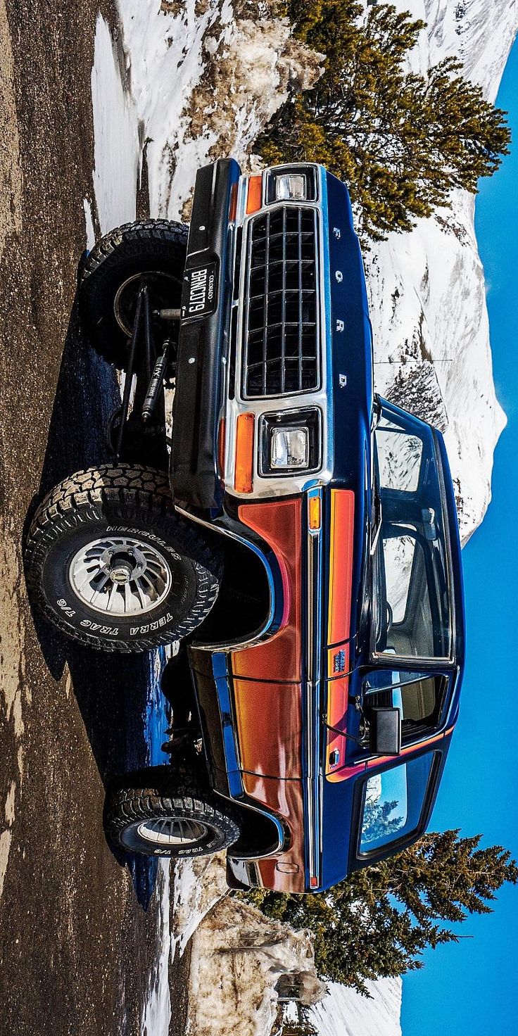 an orange and blue truck parked on the side of a mountain