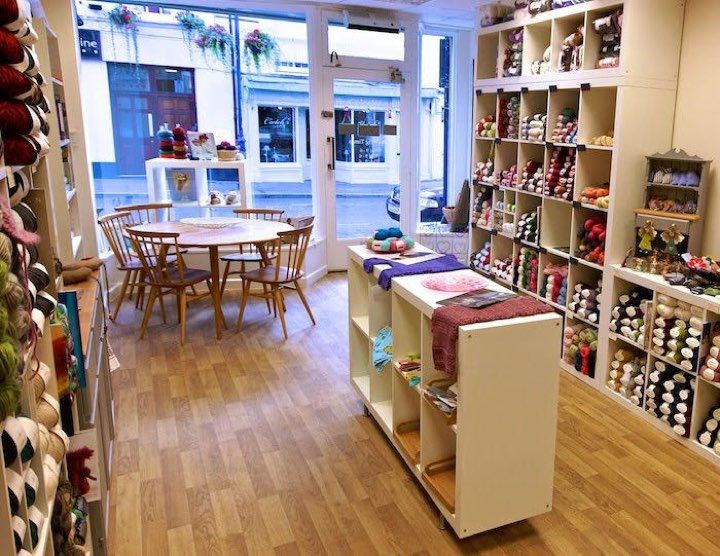 the inside of a store with many items on shelves and tables in front of it