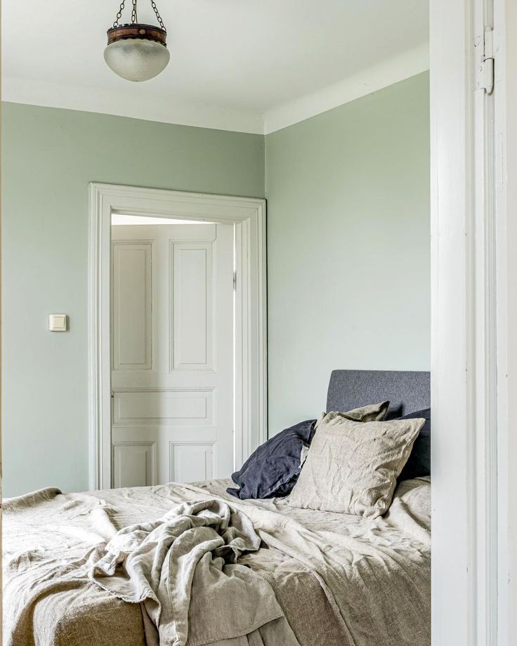 a bed sitting in a bedroom next to a white door with a light hanging above it