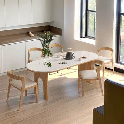 a white table with four chairs in front of a window and some plants on it