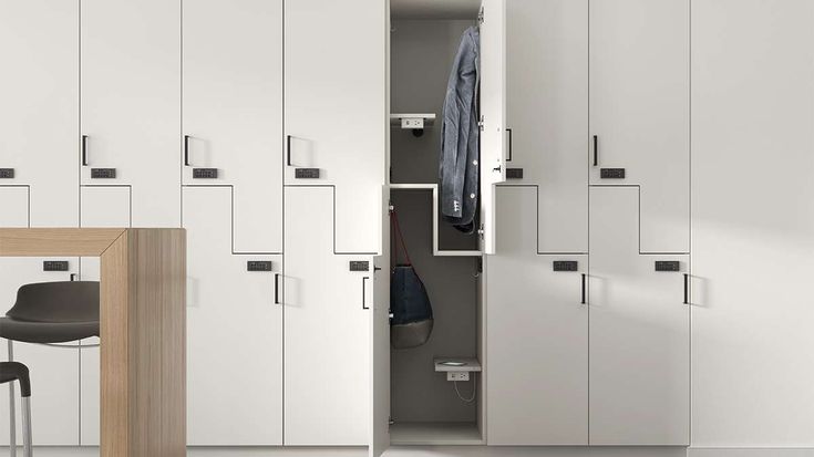 a room with white cupboards and a wooden table in it, next to a chair