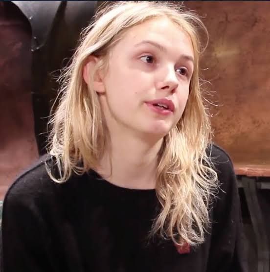 a woman with blonde hair sitting in front of a table