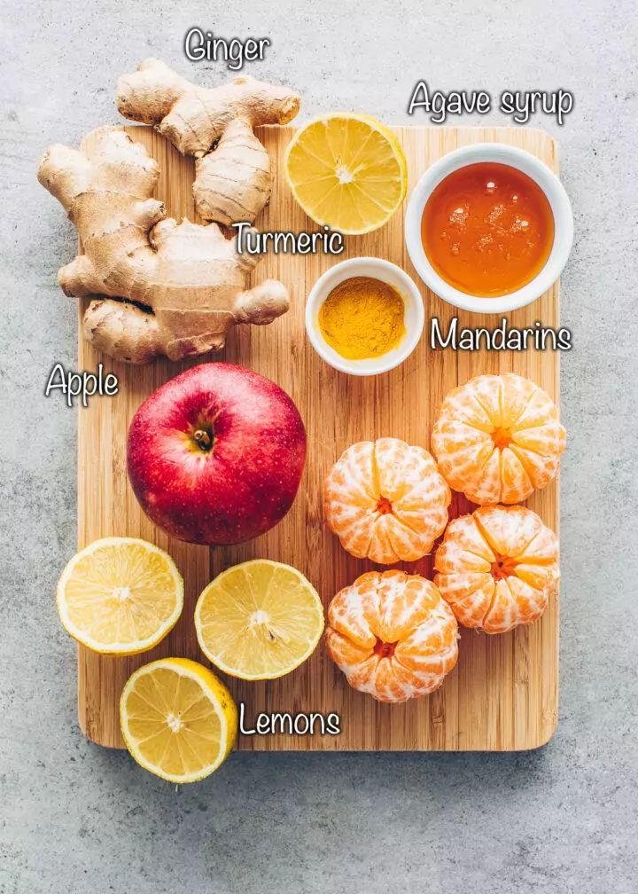 the ingredients to make an apple cider recipe on a cutting board with lemons and ginger