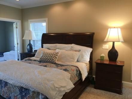 a bedroom with a bed, night stand and two lamps on either side of the bed