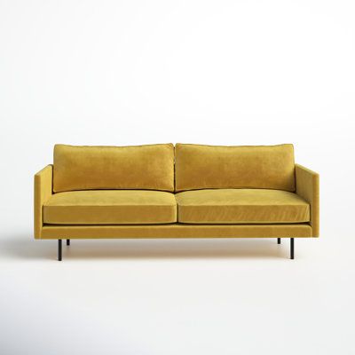 a yellow couch sitting on top of a white floor next to a black metal frame