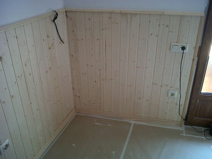 an empty room with wood paneling on the walls and floor is being painted white