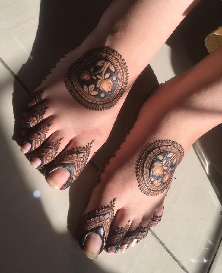 two feet with henna tattoos on them and one foot in the shape of a circle