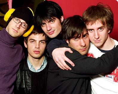 a group of young men standing next to each other in front of a red wall