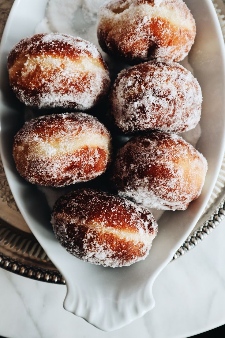 powdered sugar covered donuts on a white plate