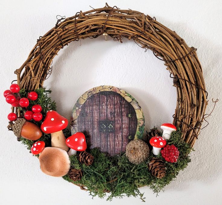 a fairy door surrounded by mushrooms and pinecones on a white wall behind a wicker wreath