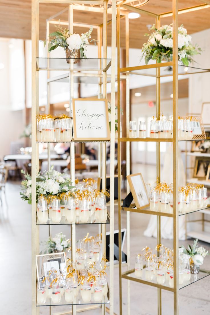 a display case filled with lots of glasses and flowers on top of shelves in a room