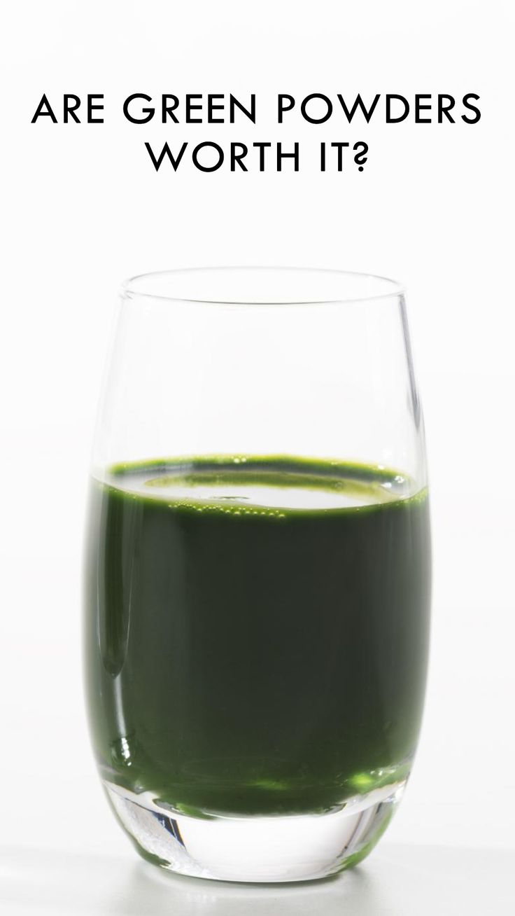 a glass filled with green liquid sitting on top of a table