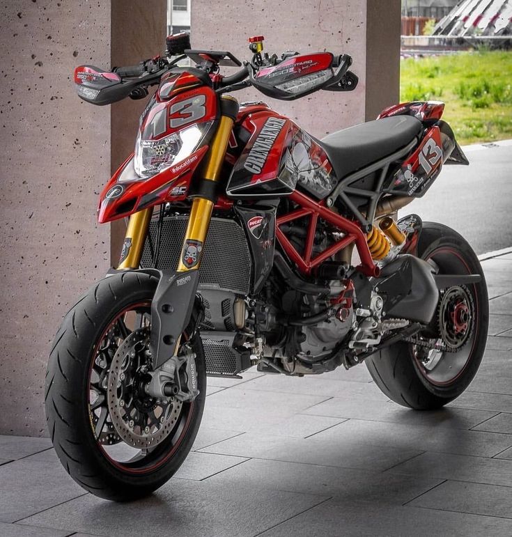 a red and black motorcycle parked next to a building