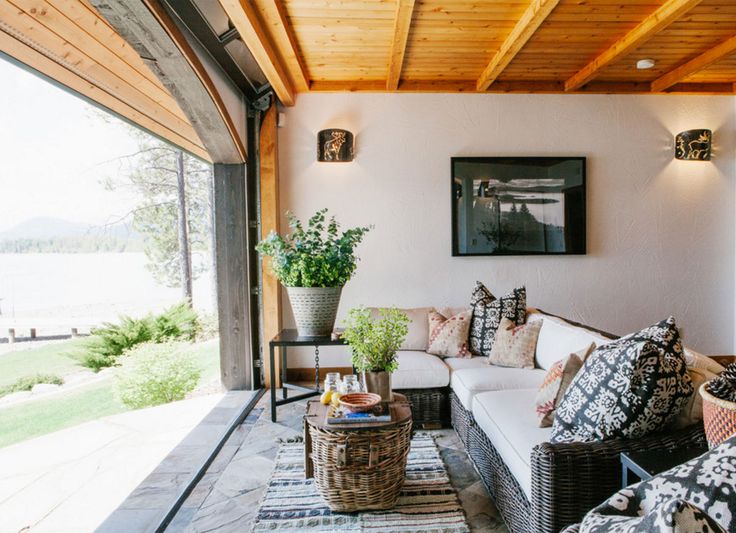 a living room filled with lots of furniture under a wooden ceiling next to a window