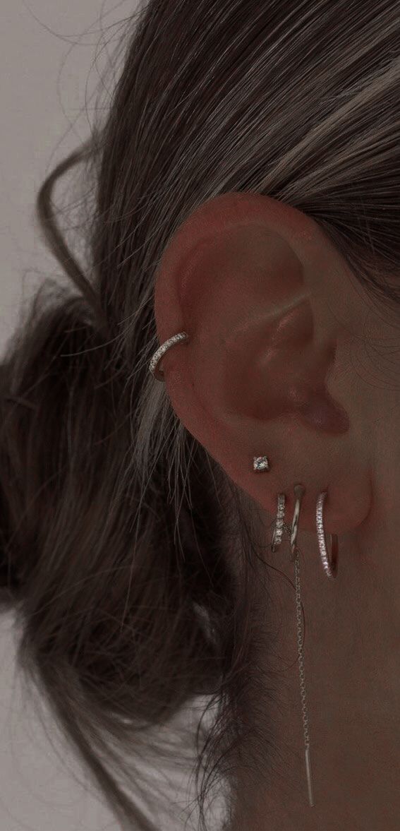 a woman wearing two silver ear cuffs with chains attached to the back of her ear