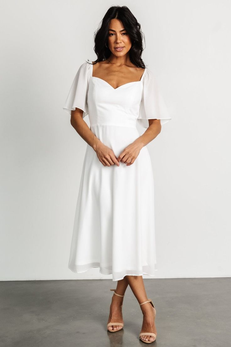 a woman in a white dress posing for the camera with her hands on her hips