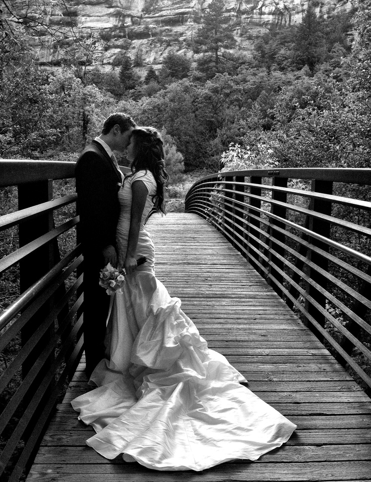 a bride and groom kissing on a bridge