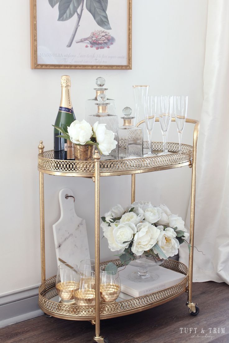 a gold bar cart with wine glasses and flowers