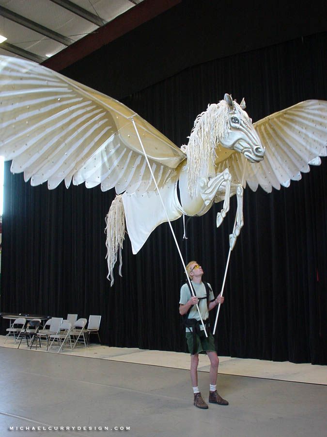 a man standing in front of a large white horse statue with wings and legs spread