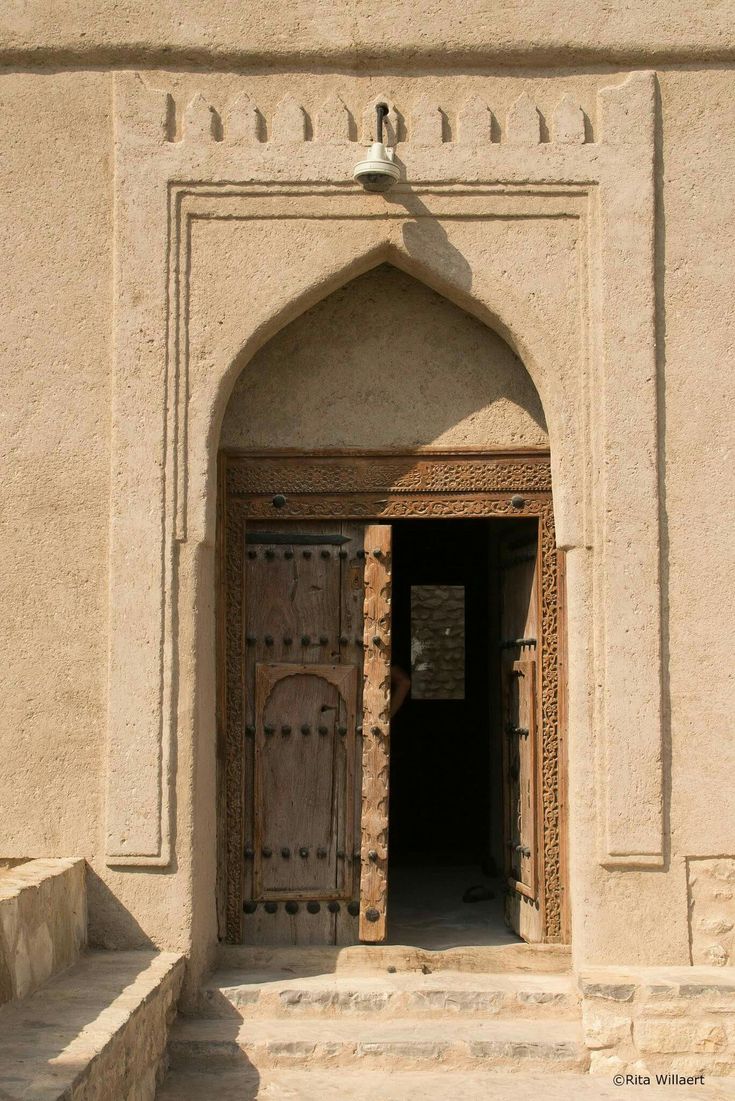 an entrance to a building with steps leading up to it and a bell on the wall