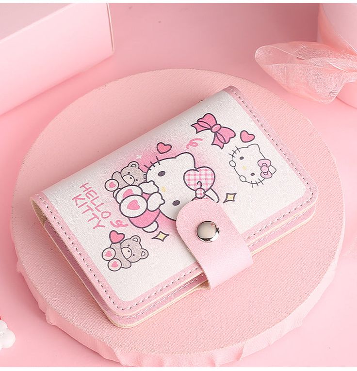 a hello kitty wallet sitting on top of a pink table