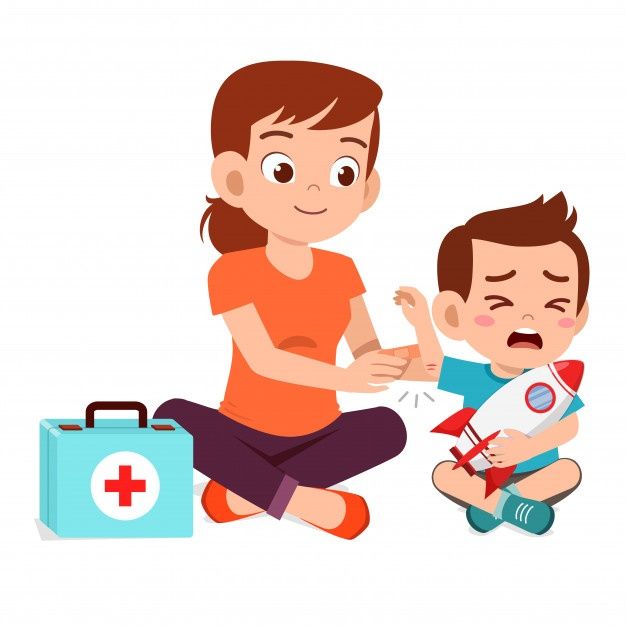 a little boy sitting on the floor next to a woman who is holding a first aid kit