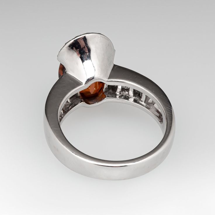 a silver ring with an orange stone in the center and two smaller stones on each side