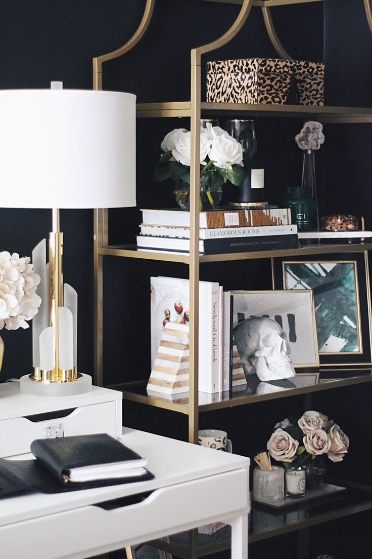 a white desk topped with a gold shelf filled with books