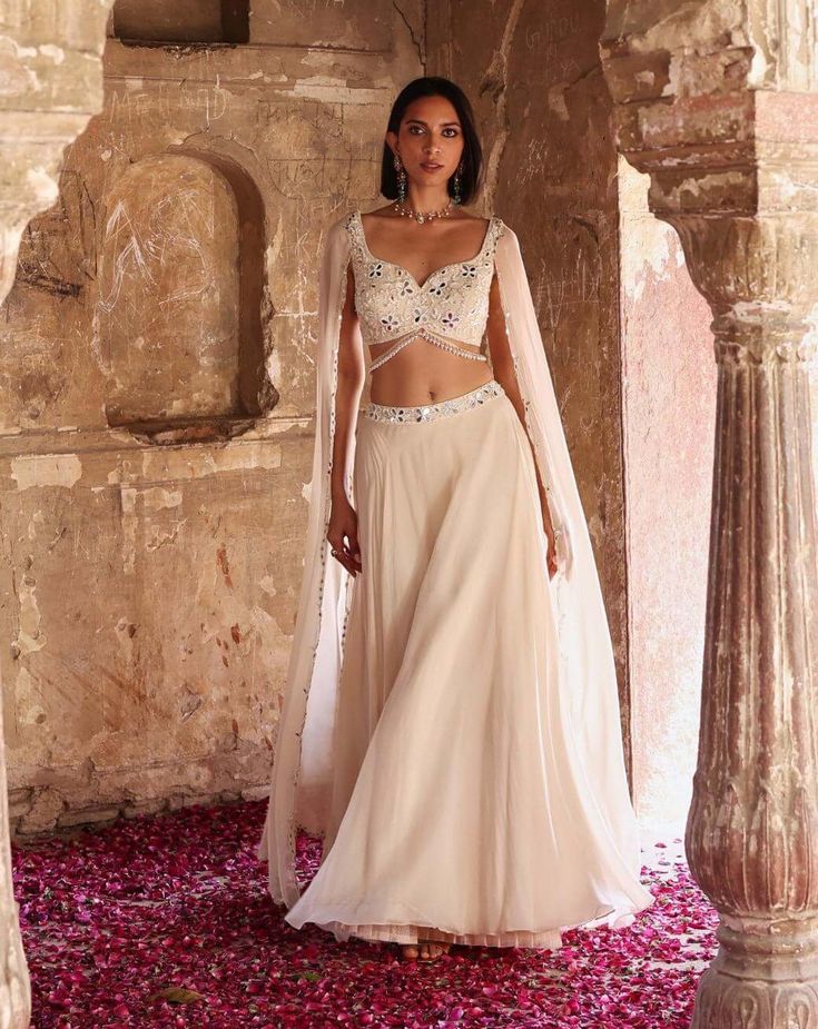 Indulge in sophistication with this embellished choli featuring attached flared sleeves, perfectly paired with a circular skirt adorned with an embellished belt and can-can detailing. This ensemble epitomizes elegance, offering a seamless blend of traditional charm and contemporary flair. Make a statement at any event or celebration with this exquisite outfit that exudes grace and style. Luxury Festive Choli With Flared Skirt, Luxury Traditional Flared Skirt, Elegant Formal Organza Lehenga, Elegant Festive Lehenga With Flowy Skirt, Elegant Gown With Pearl Embroidery For Designer Wear, Glamorous Formal Lehenga With Sheer Dupatta, Elegant Hand Embellished Sharara For Formal Occasions, Glamorous Hand Embellished Lehenga For Formal Events, Glamorous Embellished Formal Lehenga