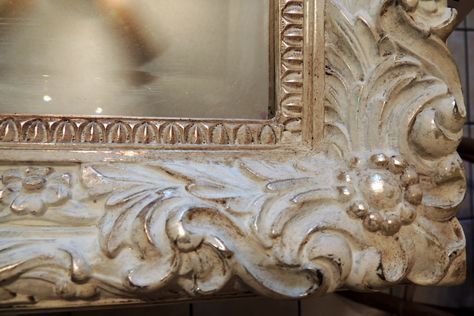 an ornate white frame holding a large mirror