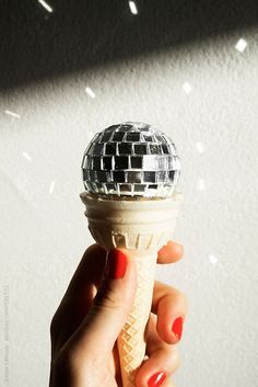 a person holding an ice cream cone with a disco ball on it's top