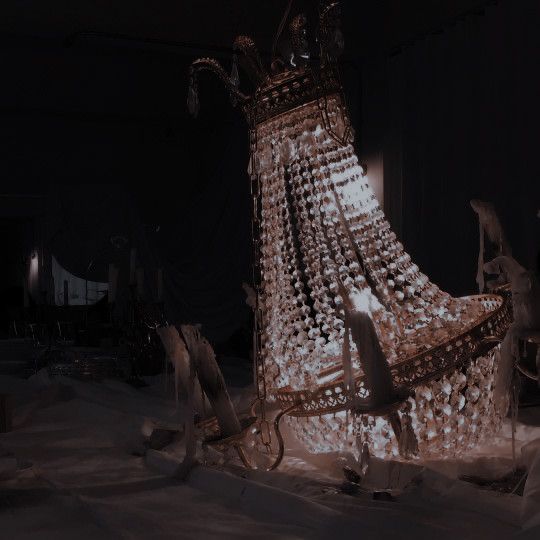 an elaborate chair made out of glass bottles in the dark with other objects around it