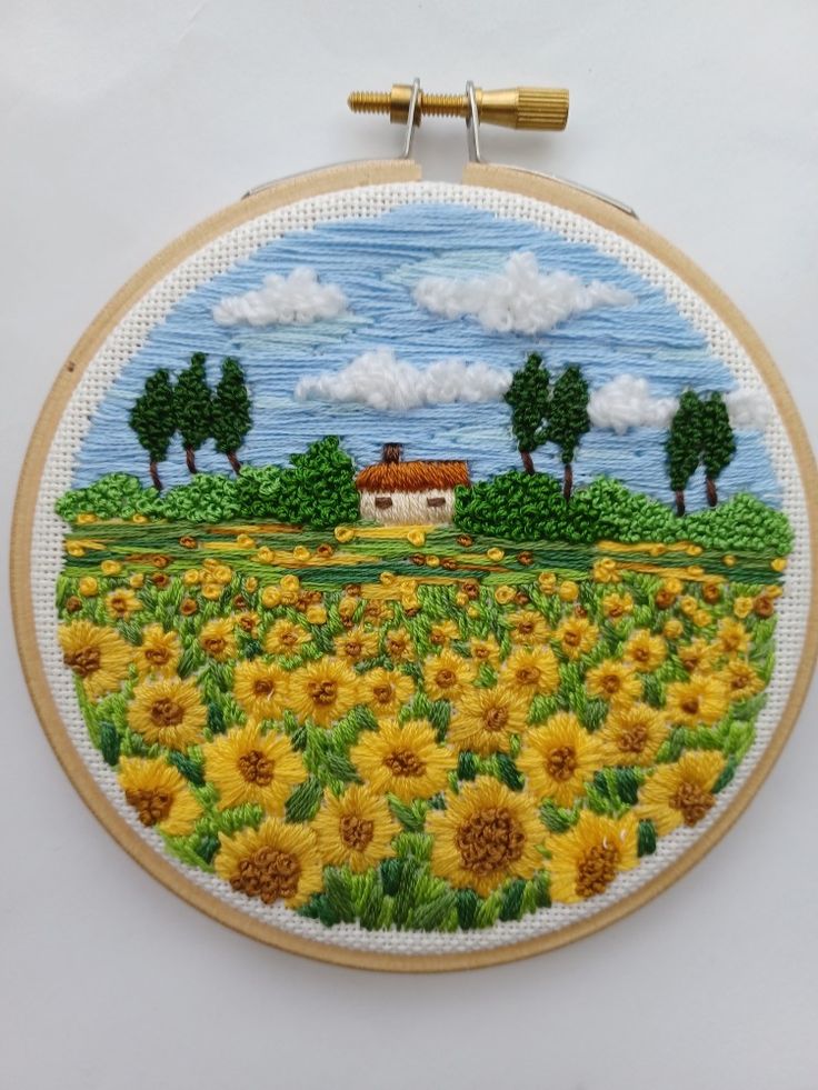 an embroidery project with sunflowers and a house in the background