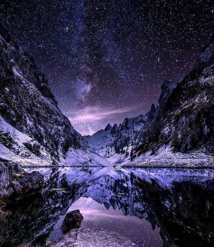 the night sky is reflected in a mountain lake with snow on it and stars above