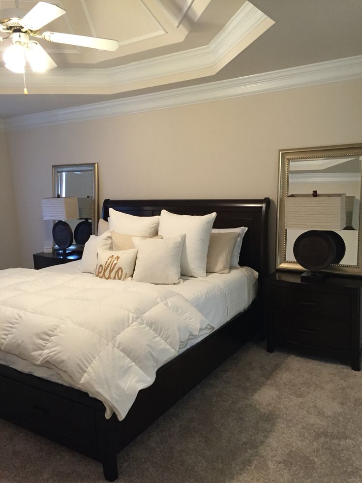 a bedroom with a large bed and white comforter on top of it, along with two night stands