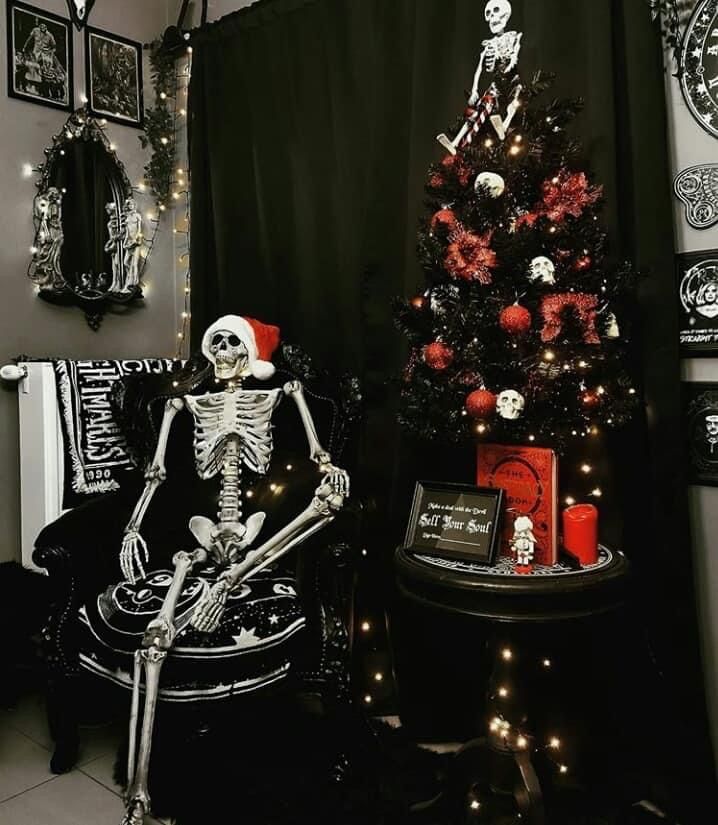 a skeleton sitting in a chair next to a christmas tree