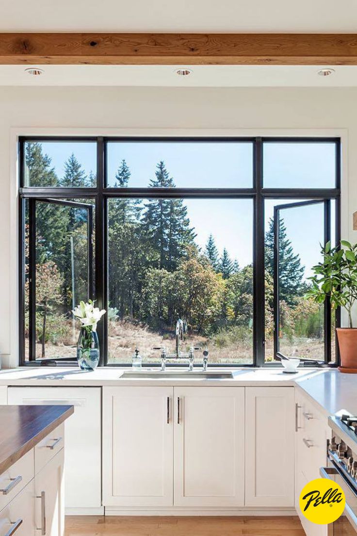 a kitchen with lots of windows and white cabinets in front of the window is a potted plant