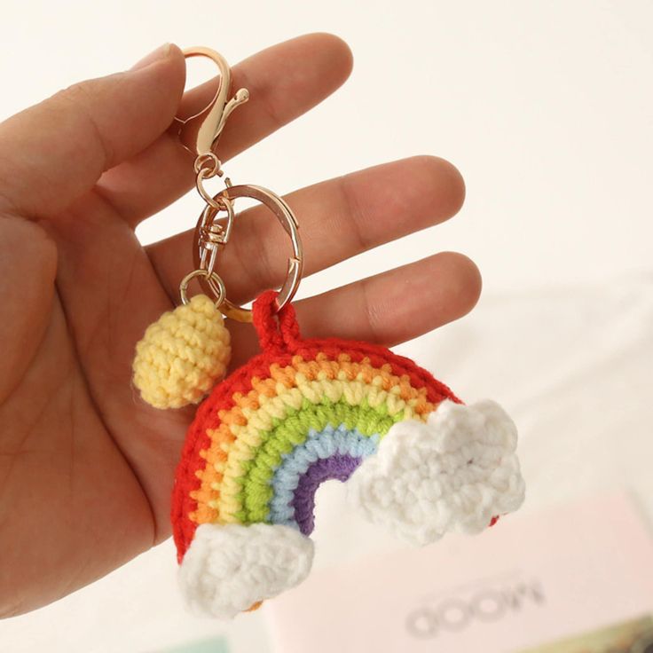 a hand holding a crocheted keychain with a rainbow on it