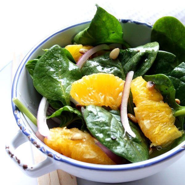 a bowl filled with spinach, oranges and onions