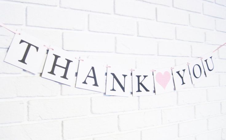 a thank you sign hanging on a brick wall next to a pink heart shaped balloon