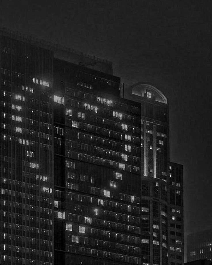 black and white photograph of skyscrapers in the city at night with lights shining on them