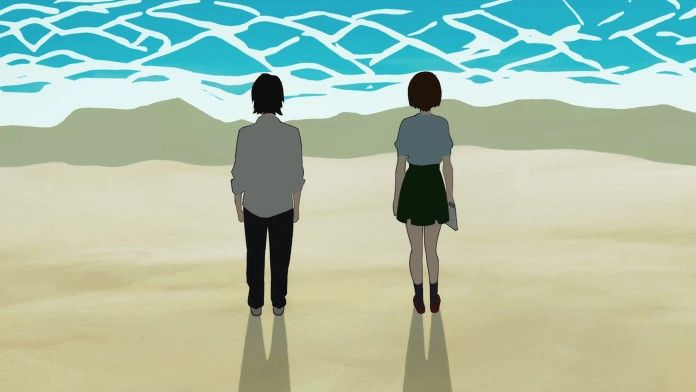 two people standing on the beach looking out at the ocean