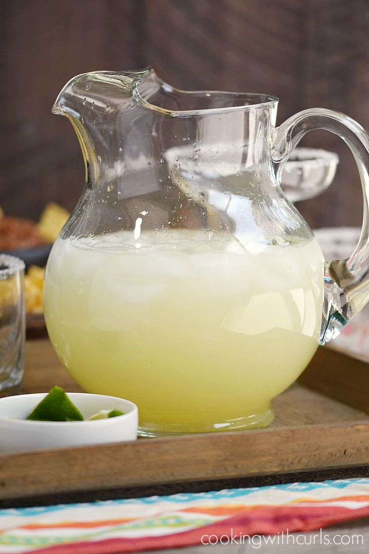 a pitcher filled with liquid sitting on top of a wooden tray