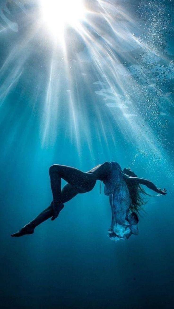 a woman is floating in the water with her legs spread out and head tilted to the side