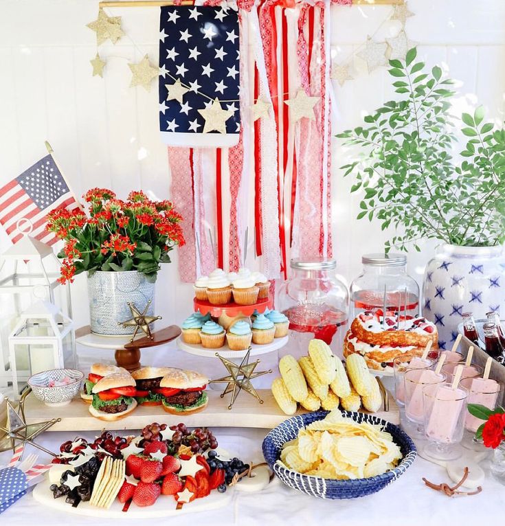 an american flag dessert table with cupcakes, cookies and other treats on it