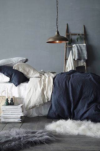 an image of a bed with blue sheets and blankets on it, next to a stack of books