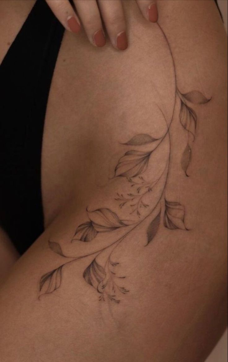 a woman's thigh with flowers and leaves on it