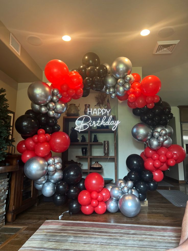 a happy birthday balloon arch with red, black and silver balloons